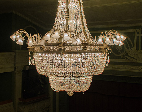 a chandelier suspended above a theater's stage and box seats