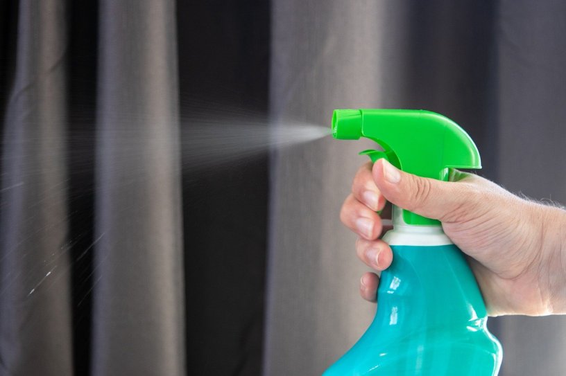 image of a hand holding and spraying disinfectant from a bottle