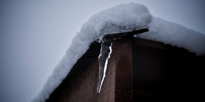 single icicle forming on edge of wood