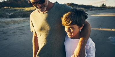 father and son enjoying a walk along the beach