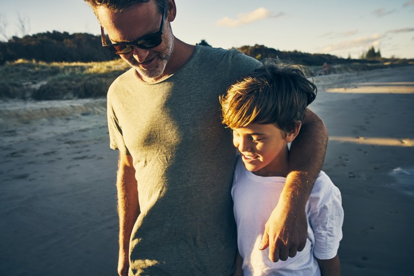 father and son enjoying a walk along the beach