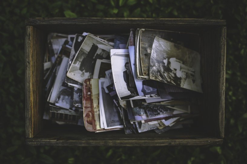 old photos piled in a wooden box