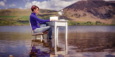 Poet Kim Moore sits at a desk resting in a lake