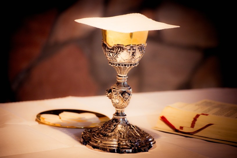 a chalice with a cross on it, prepared with the eucharist for communion