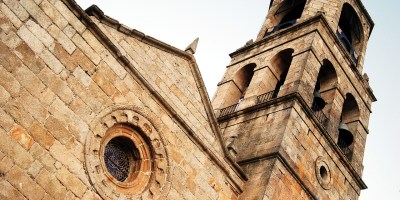 An old stone church tower with bells as seen from below