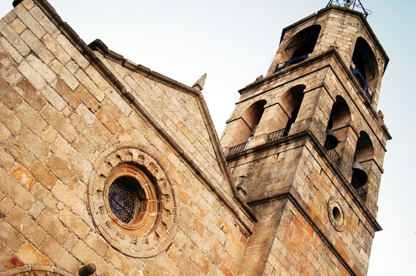 An old stone church tower with bells as seen from below