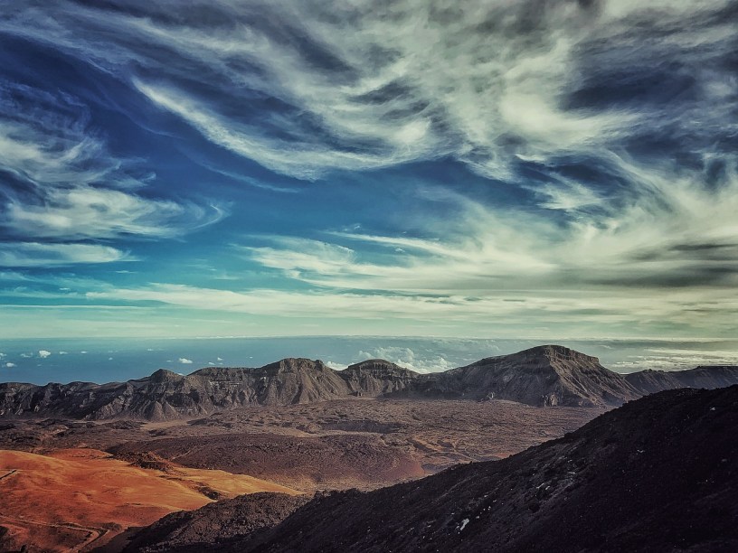 A dry valley that appears to contain a cooled and hardened lava flow, as scene from a ridgeline or volcano's rim