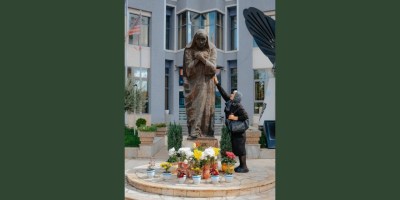 A woman touches a statue of Mother Teresa