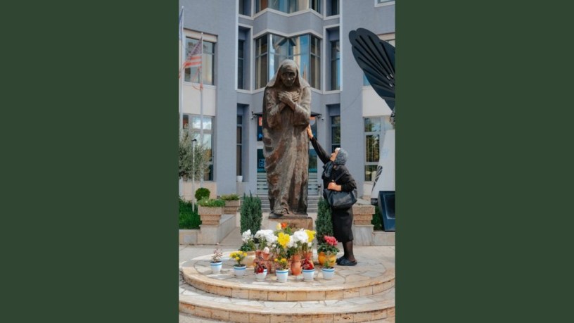 A woman touches a statue of Mother Teresa